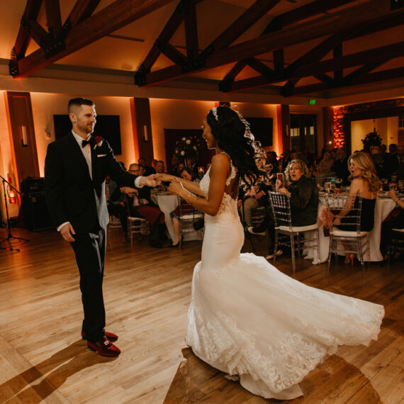 A couple dances in the dramatically lit Great Hall while their guests are seated at tables.