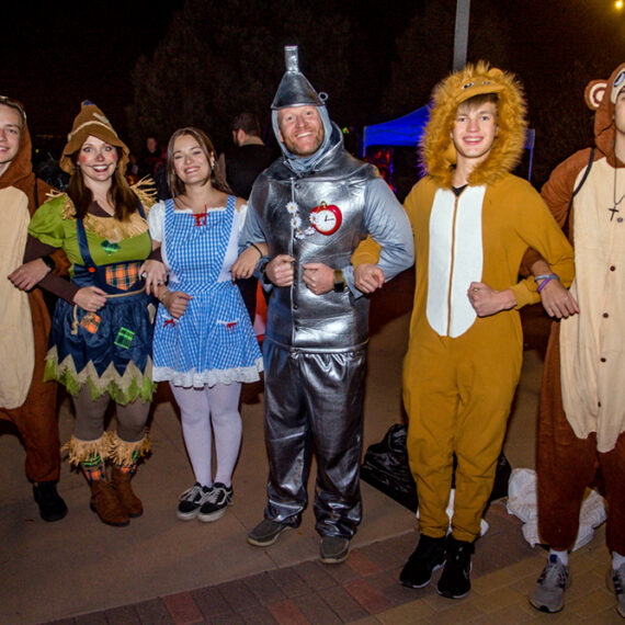 A Halloween group dressed up as a flying monkey, scarecrow, Dorothy from the Wizard of Oz, the tin man, the cowardly lion, and another flying monkey.
