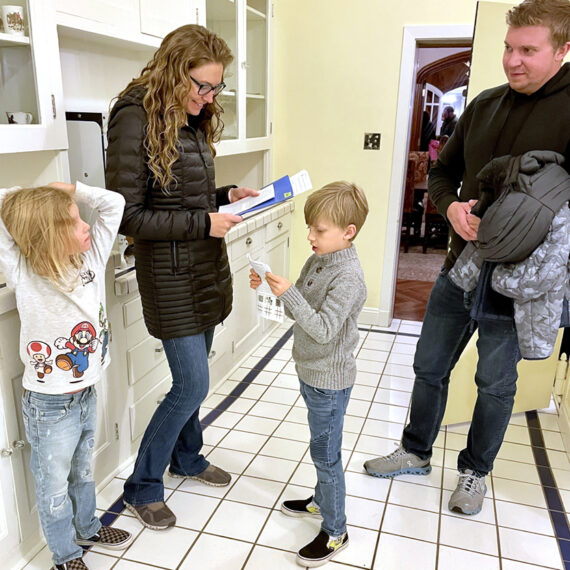 A family smiles and proceeds with a tour in the white tiled butler's pantry of the Mansion.