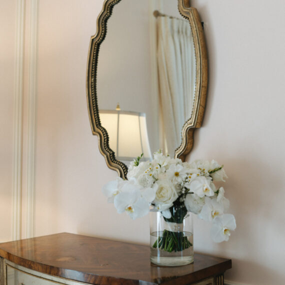 An oval mirror and nightstand in the Bridal Suite accompanied by a beautiful bridal bouquet.