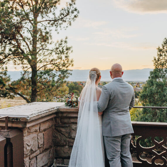 Bride and groom embrace while overlooking the Mansion grounds on the west balcony.