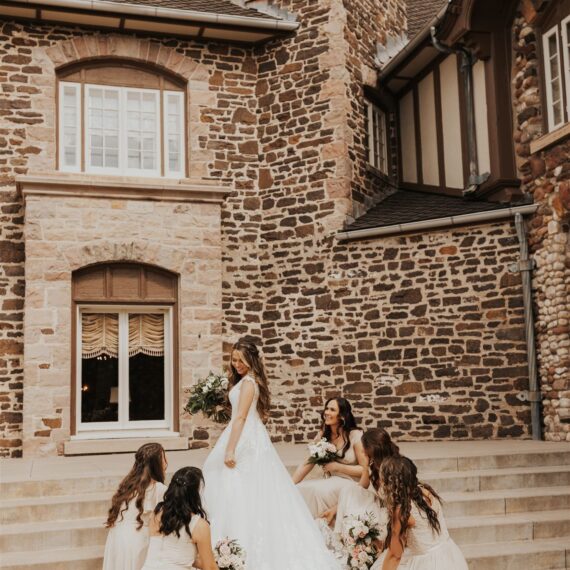 Bridesmaids fix the bride's wedding dress to make it perfectly cascade down the Veranda steps.
