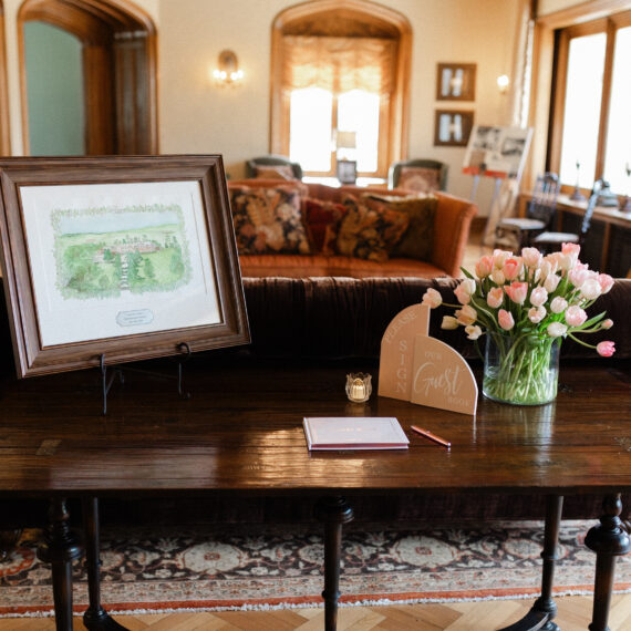 The sofa table in the Living Room is displayed with a guest book and florals.