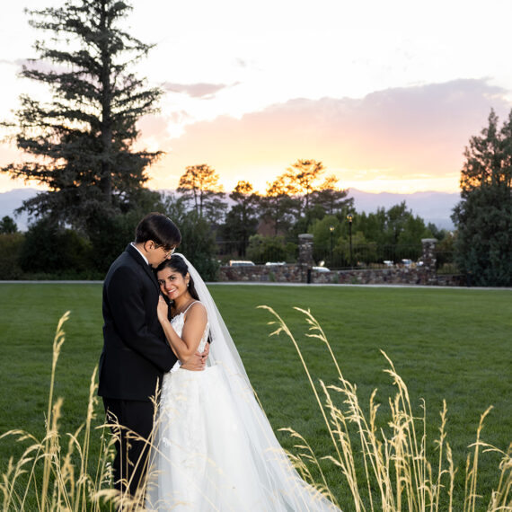 A bride and groom embrace on the West Lawn during a sunset.