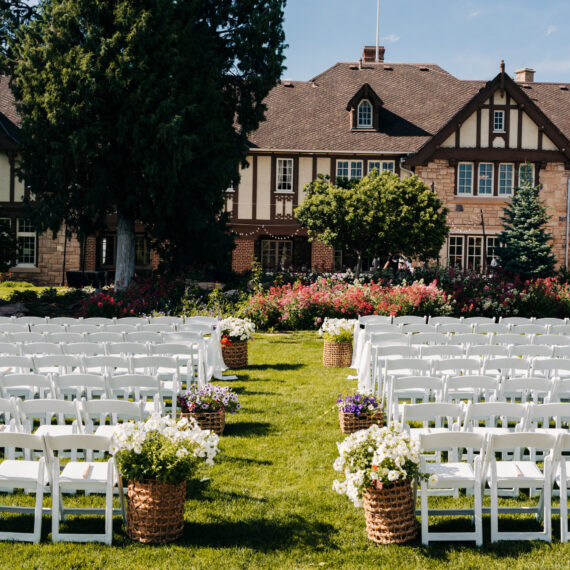 The back lawn set up for a ceremony with white folding chairs.