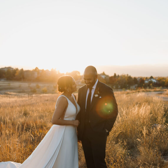 Bride and groom smile at each other on the Mansion grounds during golden hour creating a warm glow.