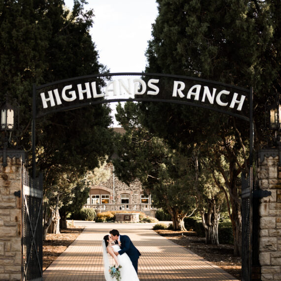 Bride and groom stand underneath the Highlands Ranch gate sign.