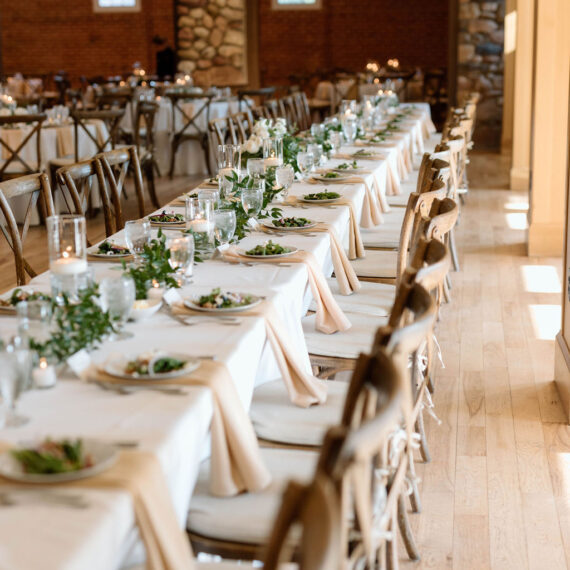 A long farmhouse table lines the Great Hall with place settings set for guests.