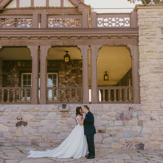 Bride and groom kiss in front of the Mansion's west balcony.
